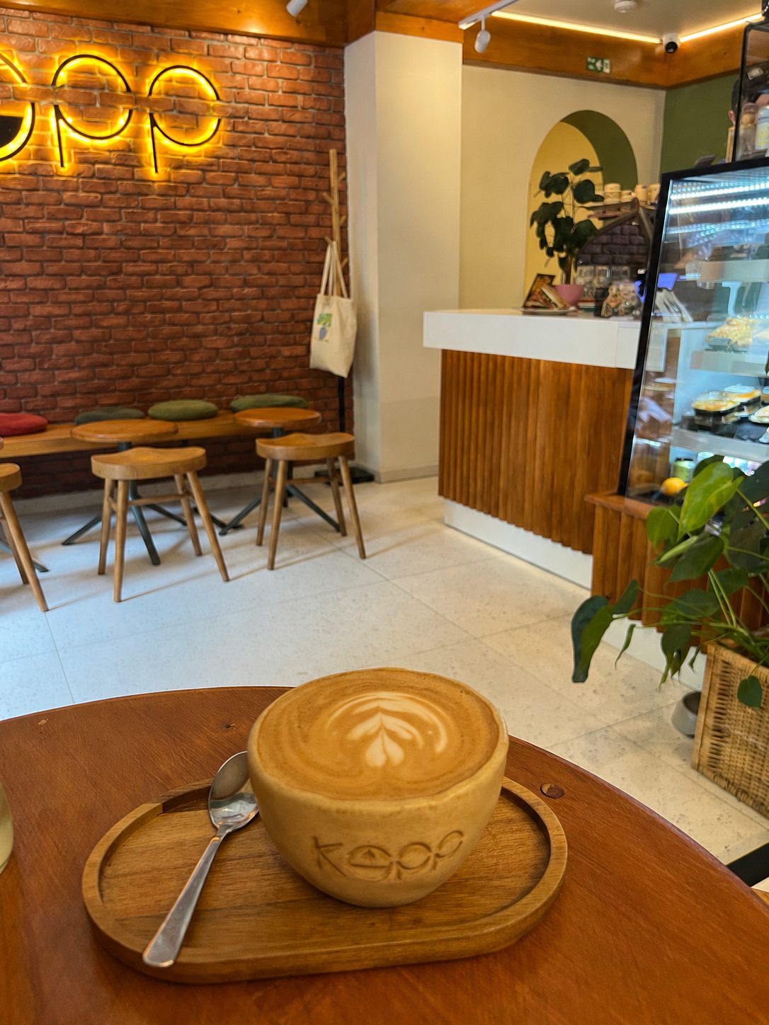 Cappuccino în ceașca de ceramică KOPP, cu logo-ul neon în fundal