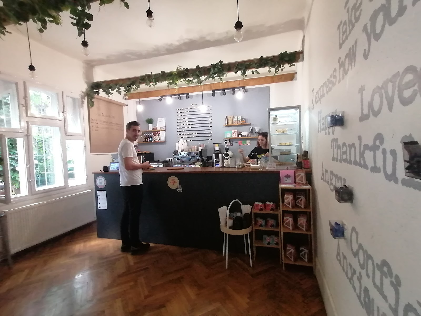 Interiorul cafenelei cu peretele plin de cuvinte-emoții și tejgheaua de lemn