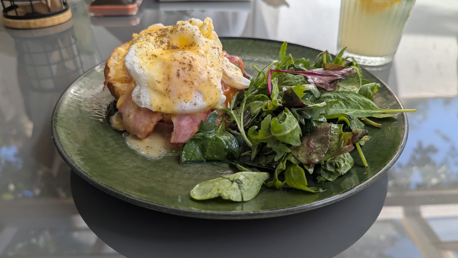 Ouă Benedict cu salată verde pe farfurie de ceramică verde la Food and Stories